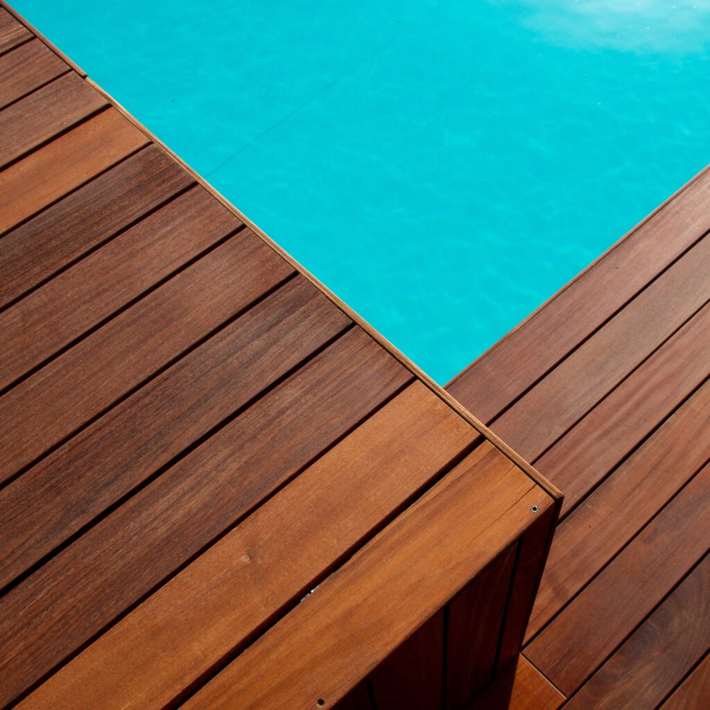 Diagonal line of exotic hardwood in detail decking around the blue water swimming pool corner